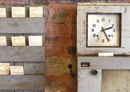 Antique time stamp clock in papers and clock face against a rustic brick wall