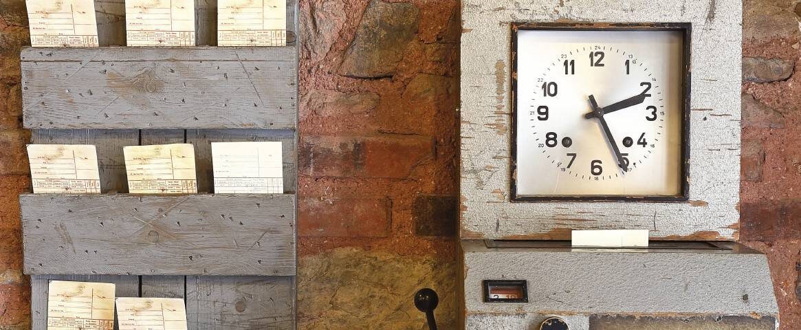 Antique time stamp clock in papers and clock face against a rustic brick wall