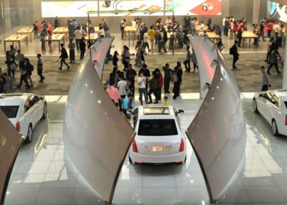 indoor showroom with cars and people