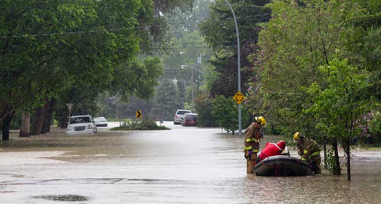 flooded street leaves man in the middle of the street being rescued by firemen