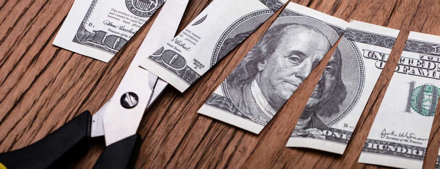 cutting one hundred dollar bill with scissors