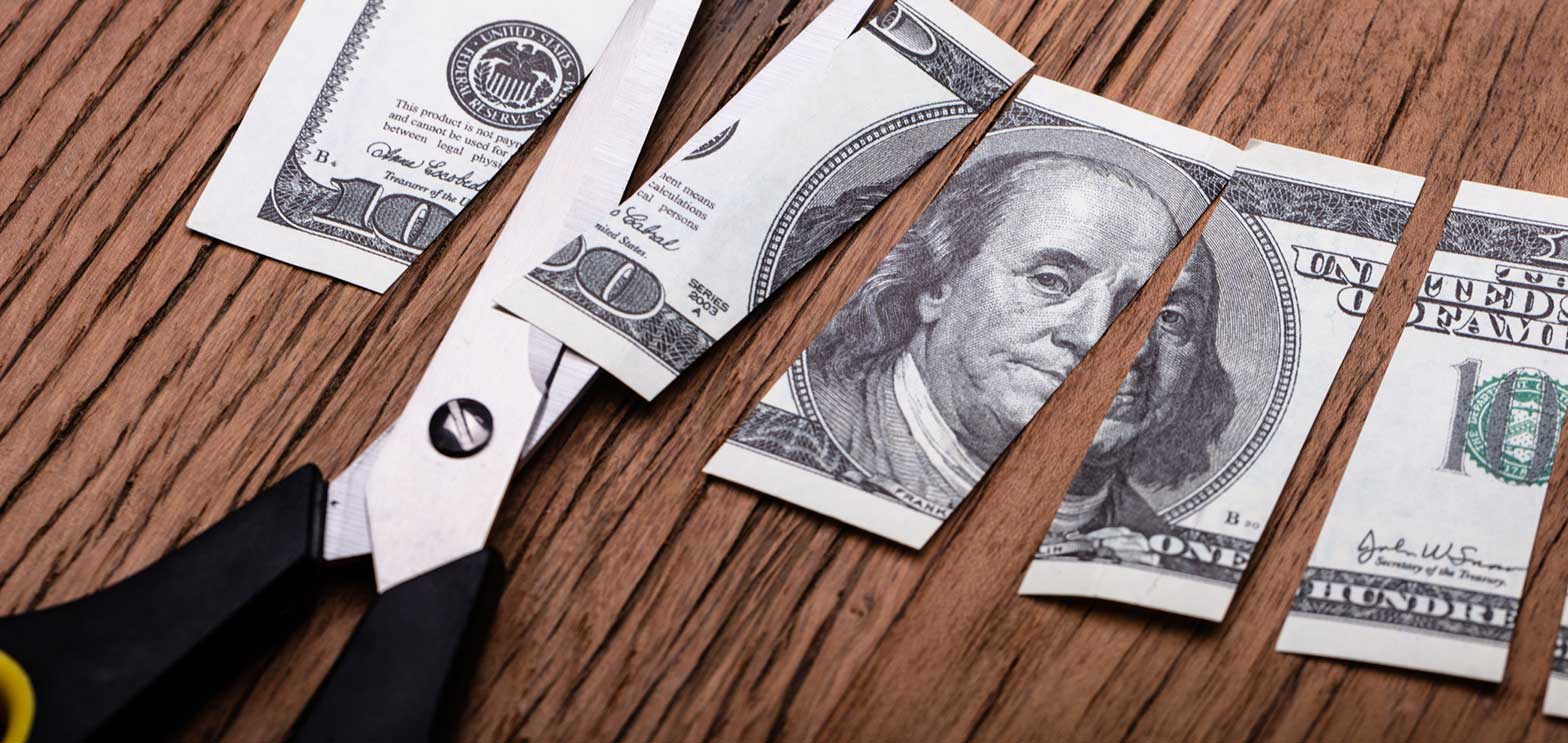 cutting one hundred dollar bill with scissors