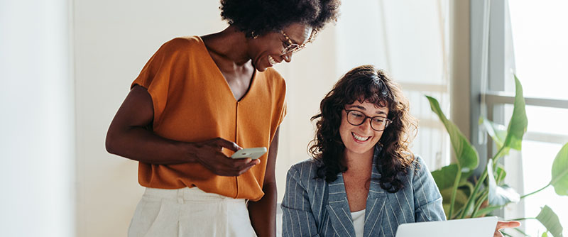 Two female entrepreneurs using a laptop for a productive business meeting.