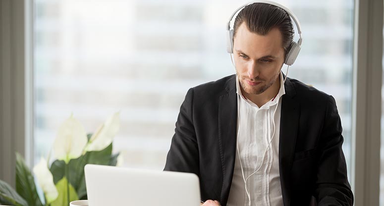 man looking at laptop with headsets on from on demand contact center solutions company