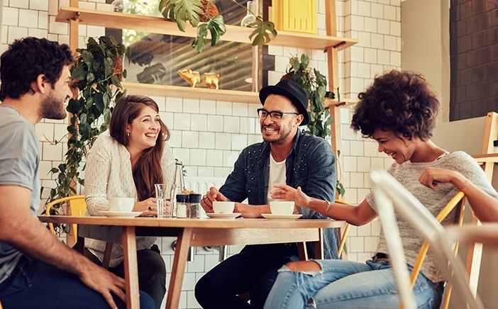 Group or friends laughing and conversing over coffee in a cafe