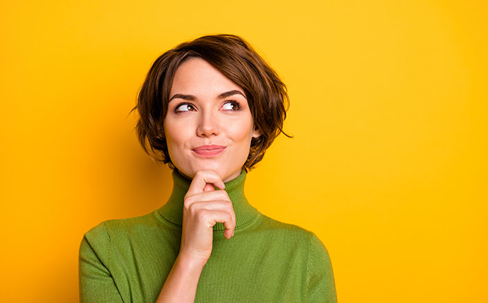 Energetic and inquisitive woman looking up in front of a yellow background