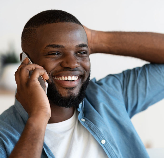 Positive black man having pleasant phone conversation