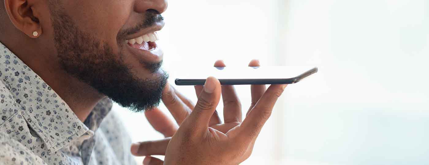 Profile of a young black man who speaks with a smile to his phone in speaker mode