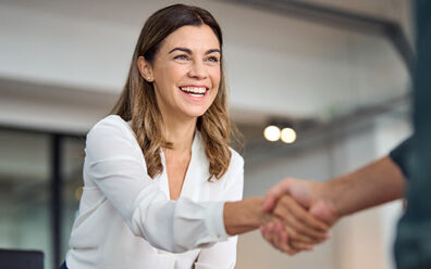 Business woman shaking hands in a corporate meeting room setting