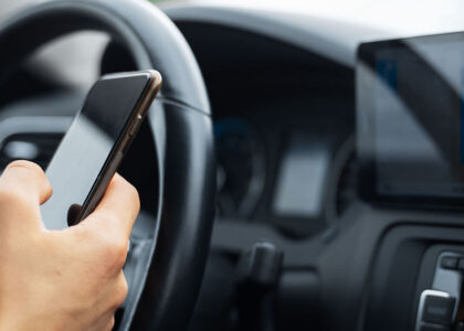 Driver holds smartphone for navigation in modern car.