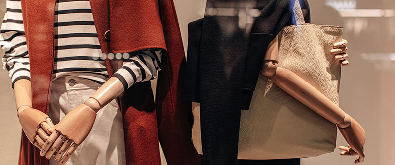 Two stylish mannequins in a store window dressed in seasonal fashion