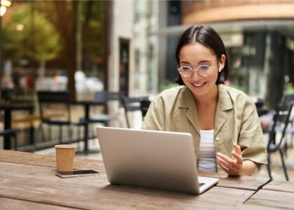 Woman enthusiastically learns via laptop conversation at a coffeeshop