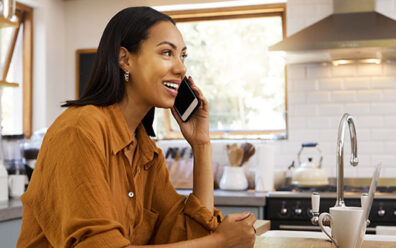 Happy customer takes phone call in her kitchen at home