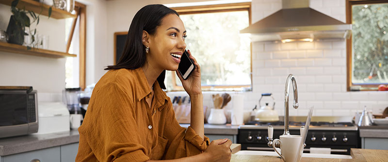 Happy customer takes phone call in her kitchen at home