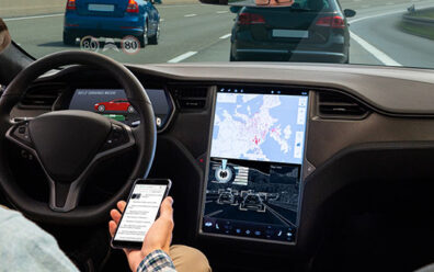 A man reads news online in a smartphone while his car is driven by an autopilot.