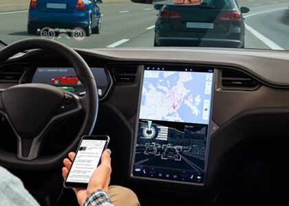 A man reads news online in a smartphone while his car is driven by an autopilot.