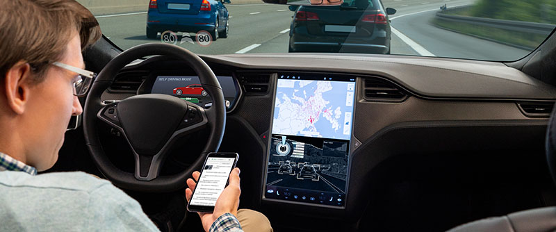 A man reads news online in a smartphone while his car is driven by an autopilot.