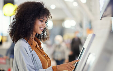 Happy customer at airport operates automatic ticket kiosk