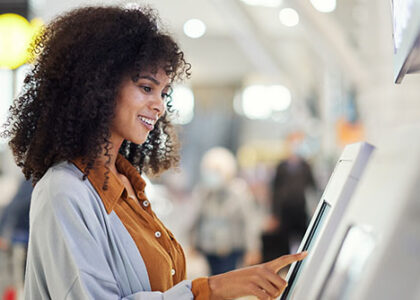 Happy customer at airport operates automatic ticket kiosk