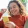 Young woman laughs at her phone as she sits on her couch at home