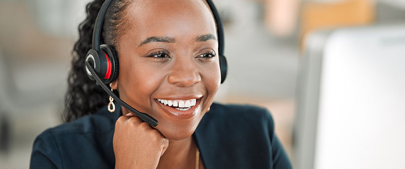 Tech savvy outsourced customer service representative cheerfully talks to a customer over the phone via headset