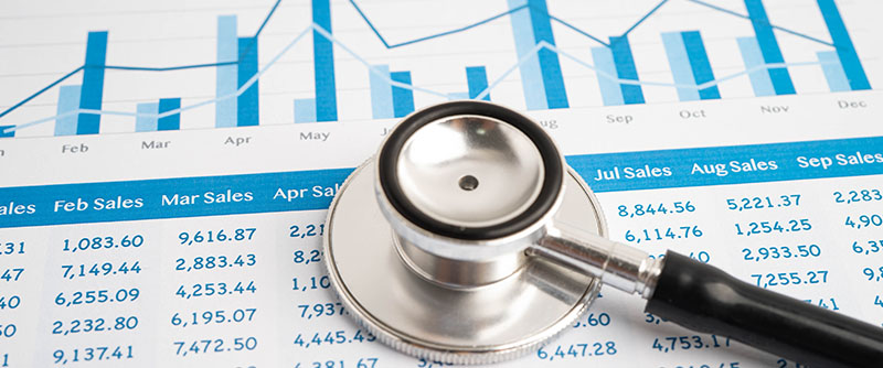 Stethoscope laying on top of a paper that displays medical sales numbers by month